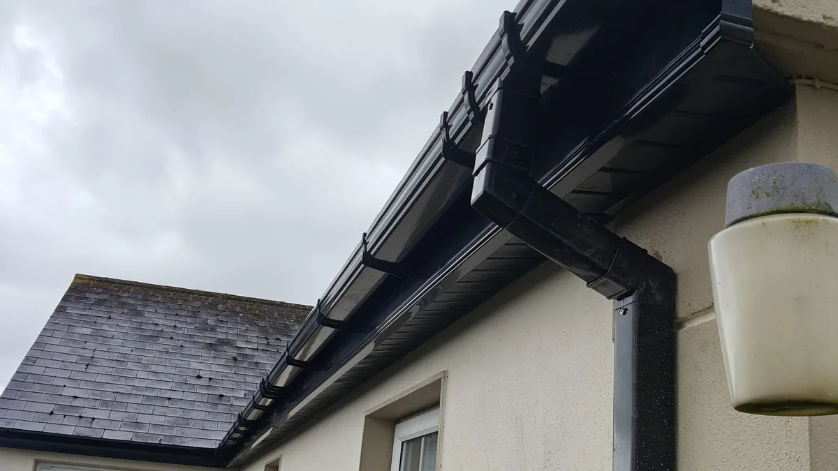 New black downpipe and gutter fitted to the side of a house